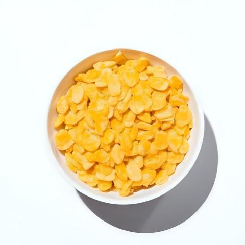 White ceramic bowl of dry uncooked corn flakess
